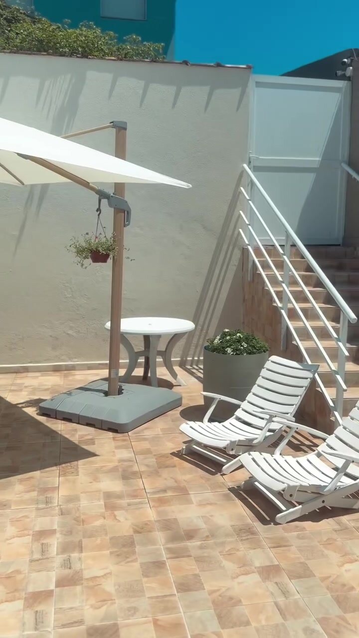 Espreguiçadeiras e guarda-sol no terraço da piscina da Casa 1.