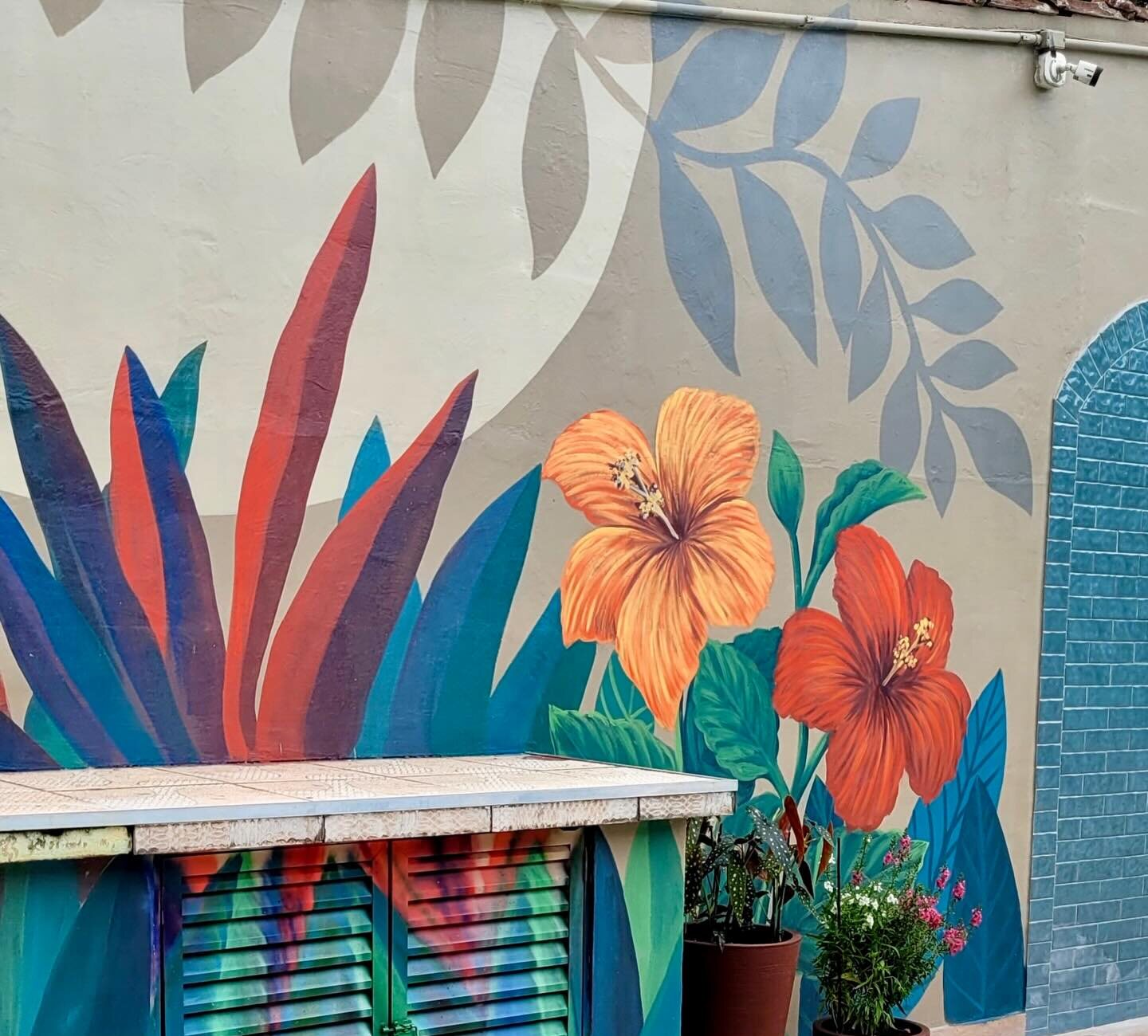 Hibiscos e folhagens do mural sobre a bancada de apoio da área da piscina.